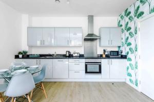 uma cozinha com armários brancos e uma mesa com cadeiras em 2 Bedroom Apartment Manchester Hosted By MCR Dens em Manchester