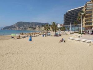 una spiaggia con persone sedute sulla sabbia e ombrelloni di FRONTIMAR a Calpe