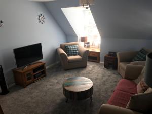 ein Wohnzimmer mit Sofas, einem TV und einem Tisch in der Unterkunft The Snug @ the Mill Inn, Stonehaven in Stonehaven