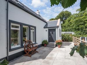a small house with a patio and a wheel at Squirrel Cottage in Stranraer