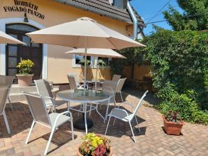 eine Terrasse mit einem Tisch, Stühlen und einem Sonnenschirm in der Unterkunft Horváth Fogadó Panzió in Szentendre