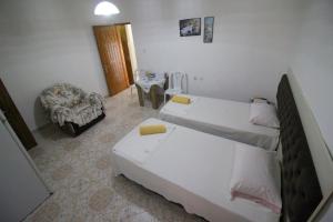 a hotel room with two beds and a chair at Mona`s apartments in Sarandë