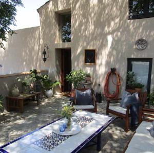un patio con mesa, sillas y pared en Casa Pura Vida, en Villanueva de Algaidas