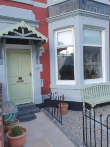 ブラックプールにあるJ's Mayfair Guest Houseの緑のドアとベンチが外にある家