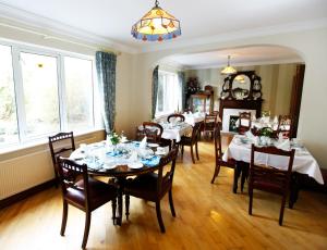 un comedor con mesas y sillas y una lámpara de araña en Ardawn House, en Galway