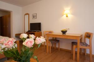 - un salon avec une table, des chaises et des fleurs dans l'établissement Rustikales Apartment 35qm mit Balkon Nähe Freiburg, à Simonswald