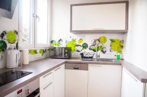 una cocina con armarios blancos y detalles verdes en Apartament Sen, en Łódź