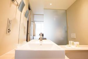 La salle de bains est pourvue d'un lavabo blanc et d'un miroir. dans l'établissement Hôtel des Voyageurs Boutique, à Lausanne