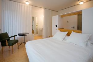 a bedroom with a large white bed and a chair at Hotel Aire de Bardenas in Tudela