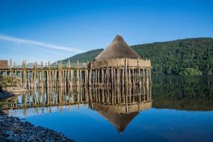 a bridge over a lake with its reflection in the water at Woodland Spruce Lodge in Killin