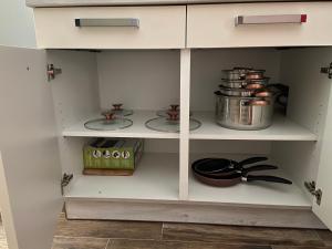 a white kitchen cabinet with pots and pans at Apartments Simoneta in Malinska +28 photos