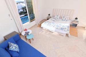 Les Deux Rives في Hammamet Sud: غرفة معيشة مع أريكة زرقاء وسرير
