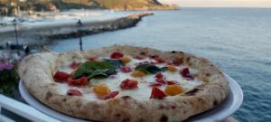 une pizza assise sur une assiette à côté de l'eau dans l'établissement Albergo Tirreno, à Marina di Camerota