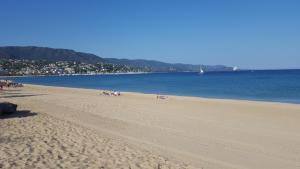plaża z ludźmi leżącymi na piasku i wodzie w obiekcie tahiti parc maisonnette 6 pers 2 chambre w mieście Le Lavandou