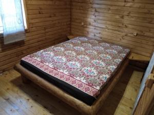 a bed in a wooden room with a quilt on it at ЗАТИШОК in Oriv