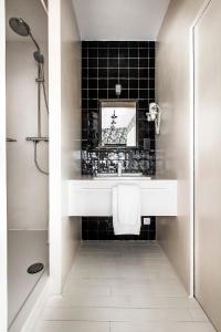 ein Badezimmer mit einem weißen Waschbecken und einer schwarzen Kachelwand in der Unterkunft La Maison Haute guesthouse in Brüssel