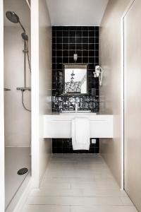 a bathroom with a white sink and a black tile wall at La Maison Haute guesthouse in Brussels