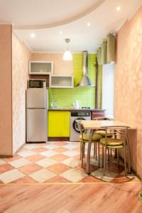 La cuisine est équipée d'une table, de chaises et d'un réfrigérateur. dans l'établissement Apartment Triokhsviatytelskaya Street 3, à Kiev