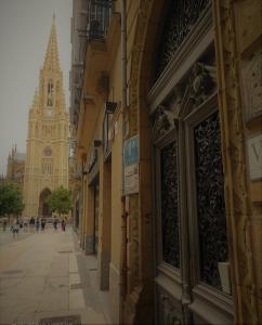 una strada con un edificio con torre dell'orologio di Pensión La Perla a San Sebastián