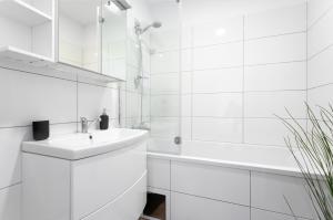 a white bathroom with a sink and a tub at Sunny Penthouse with Terrace. DG7 in Vienna