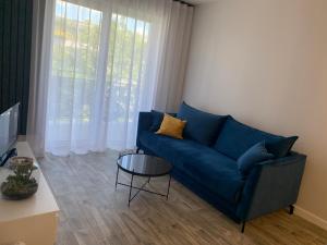 ein Wohnzimmer mit einem blauen Sofa und einem Tisch in der Unterkunft Centropolis 41 in Toruń