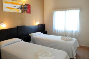 Habitación de hotel con 2 camas y ventana en Hotel El Faro en Villa Carlos Paz