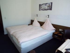 Schlafzimmer mit einem Bett mit weißer Bettwäsche und rosa Kissen in der Unterkunft Park-Hotel in Bad Hönningen