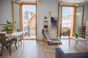 uma sala de estar com uma mesa, cadeiras e janelas em LA SURFERA APARTMENT em Tarragona