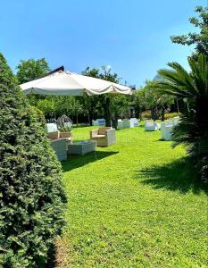 a lawn with chairs and an umbrella in the grass at Hotel Alpha in Sant'Agnello