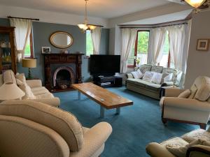 a living room with couches and a tv and a table at Wyndcliffe in Grange Over Sands