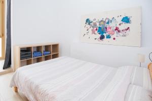 ein weißes Schlafzimmer mit einem Bett und einem Gemälde an der Wand in der Unterkunft LA SURFERA APARTMENT in Tarragona