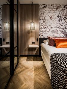 a bedroom with a bed and two tables and a wall at Hotel Van der Valk Maastricht in Maastricht