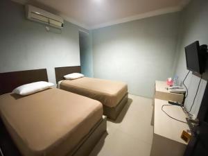 a hotel room with two beds and a television at Hotel Grand Citra Prabumulih in Perabumulih