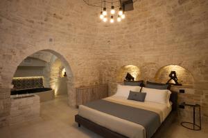 1 dormitorio con 1 cama grande en una pared de piedra en La Mandorla Luxury Trullo en Alberobello