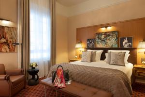 a hotel room with a bed and a chair at Hôtel Barrière Le Westminster in Le Touquet-Paris-Plage
