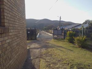 a brick wall next to a road with a fence at Kubo Bed and Breakfast in Cofimvaba