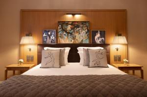 a bedroom with a large bed with pillows and paintings at Hôtel Barrière Le Westminster in Le Touquet-Paris-Plage