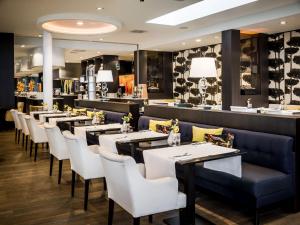 a dining room with tables and white chairs at Hotel Van der Valk Maastricht in Maastricht