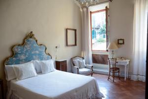 1 dormitorio con cama, ventana y silla en 1550 Residenza d’Epoca en Siena