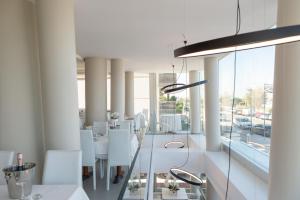 a dining room with a table and white chairs at Hotel Commodore in Cervia