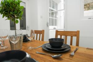 einen Holztisch mit einer schwarzen Schale sowie Teller und Weingläser in der Unterkunft Montpelier Apartment - Central - by Brighton Holiday Lets in Brighton & Hove