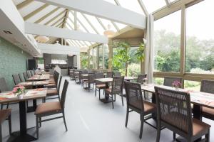 a dining room with tables and chairs and windows at Flanders Lodge Hotel in Ieper