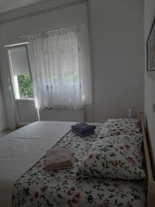 sypialnia z łóżkiem z kwiatową narzutą i oknem w obiekcie Apartment Maslina w Biogradzie na Moru