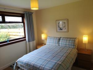 a bedroom with a bed and a window and two lamps at Newholme Self-Catering Bungalow in Pitlochry