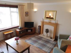 een woonkamer met een televisie en een open haard bij Newholme Self-Catering Bungalow in Pitlochry