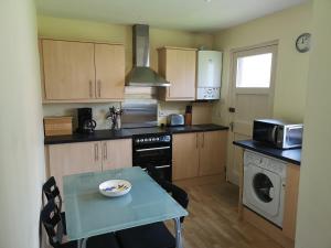 a small kitchen with a table and a microwave at Newholme Self-Catering Bungalow in Pitlochry