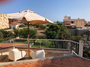 un patio con sombrilla y 2 sillas blancas en Sole e Luna en Marina di Modica