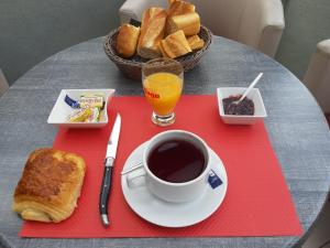 una mesa con una taza de café y un plato de pan en Hôtel Duguesclin, en La Haye-Pesnel