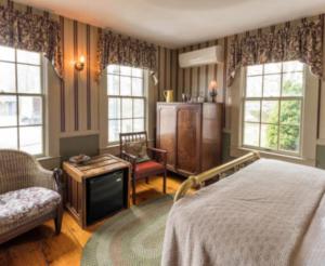 a bedroom with a bed and a tv and windows at Snug Cottage in Provincetown