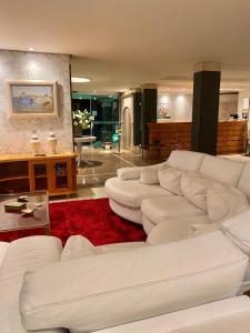 a living room with white couches and a red rug at Pousada La Barca in Torres
